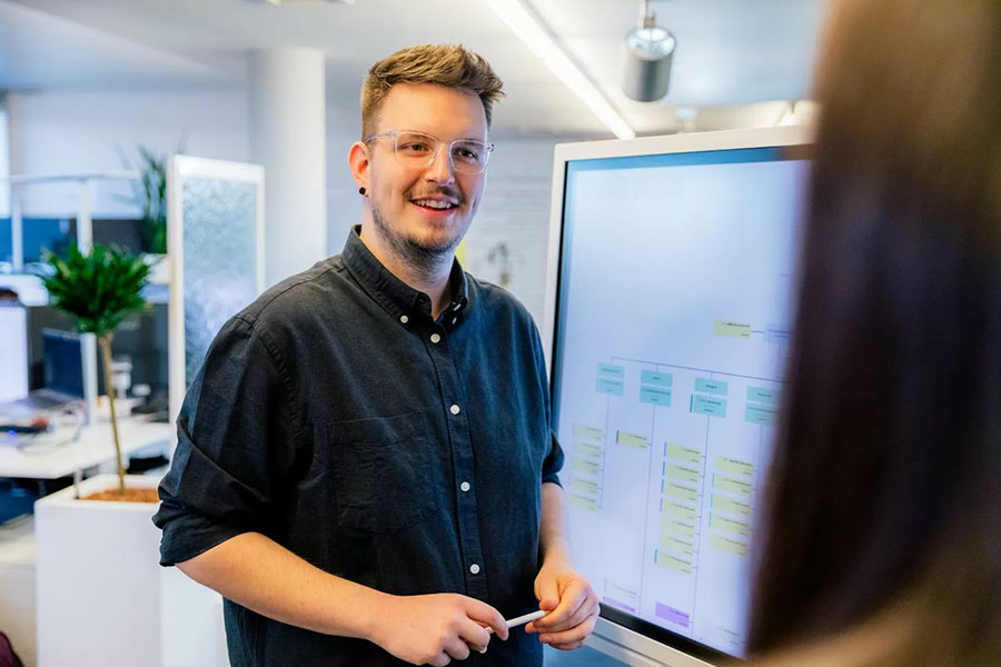 Mitarbeiter praesentiert digitale Struktur auf grossem Monitor